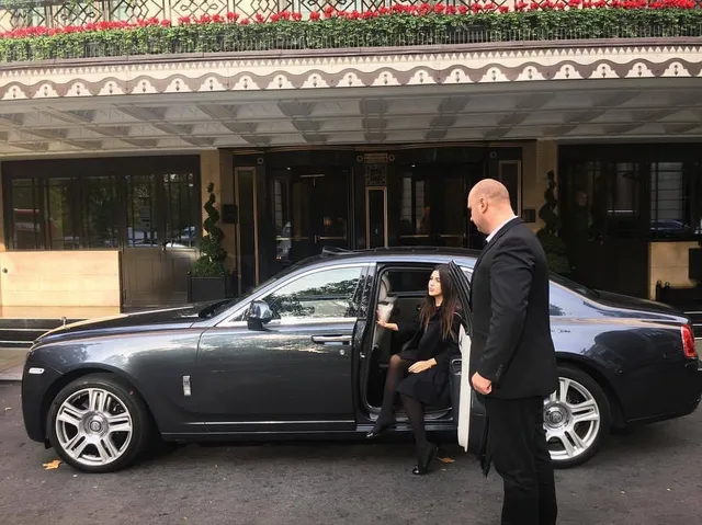 Close protection officer assisting a client from a luxury vehicle