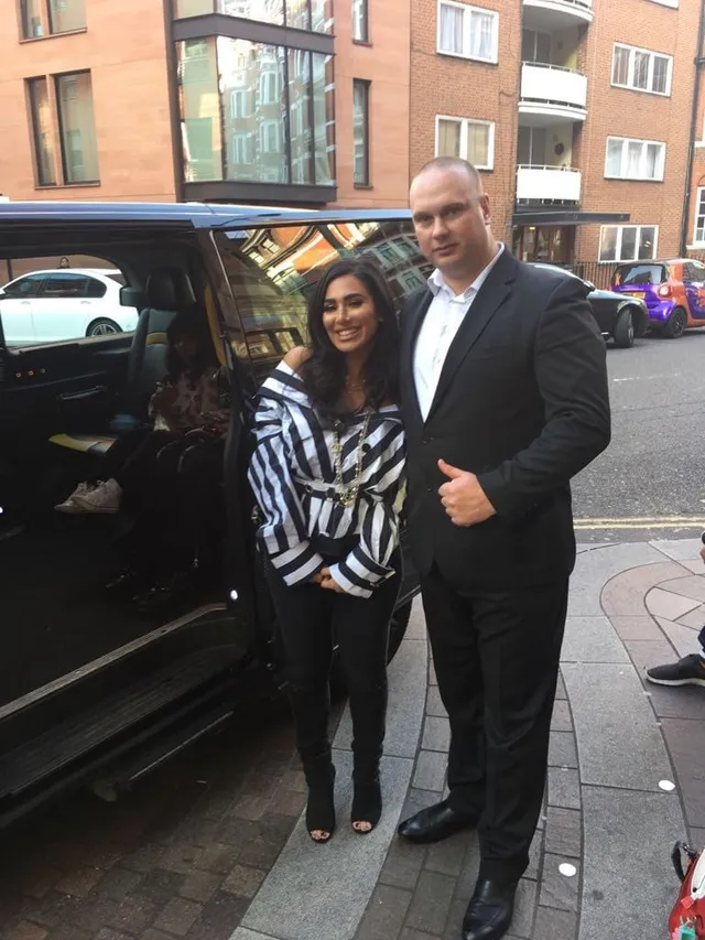 Close protection officer with a client beside a vehicle