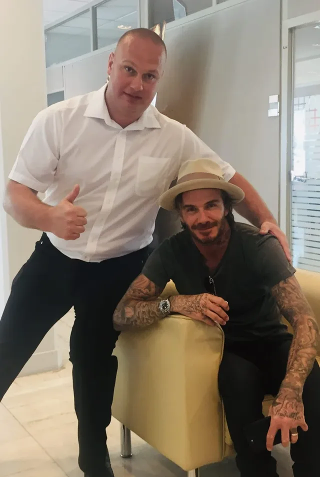 Close protection officer with a seated client indoors