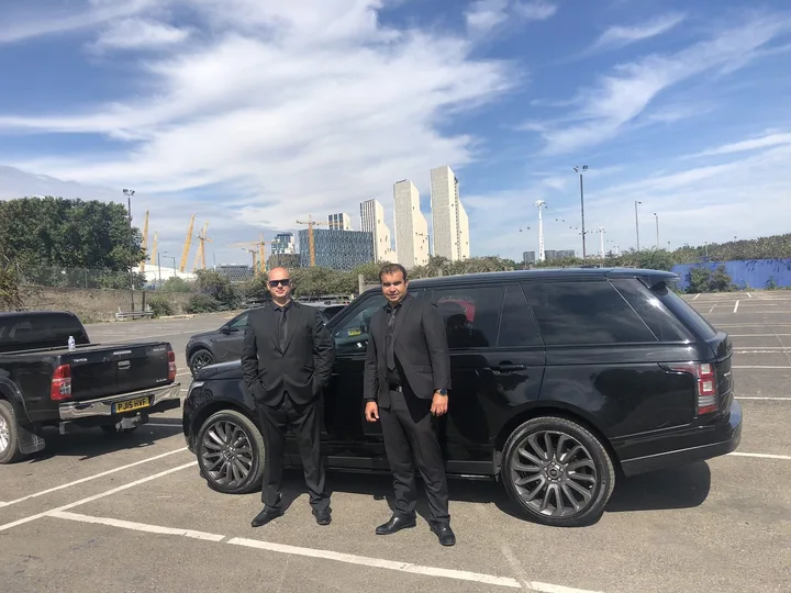 Two security officers beside a commercial patrol vehicle