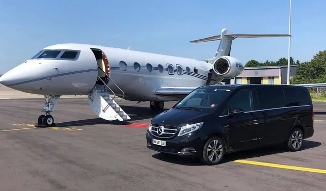 Black executive transfer vehicle beside a private jet