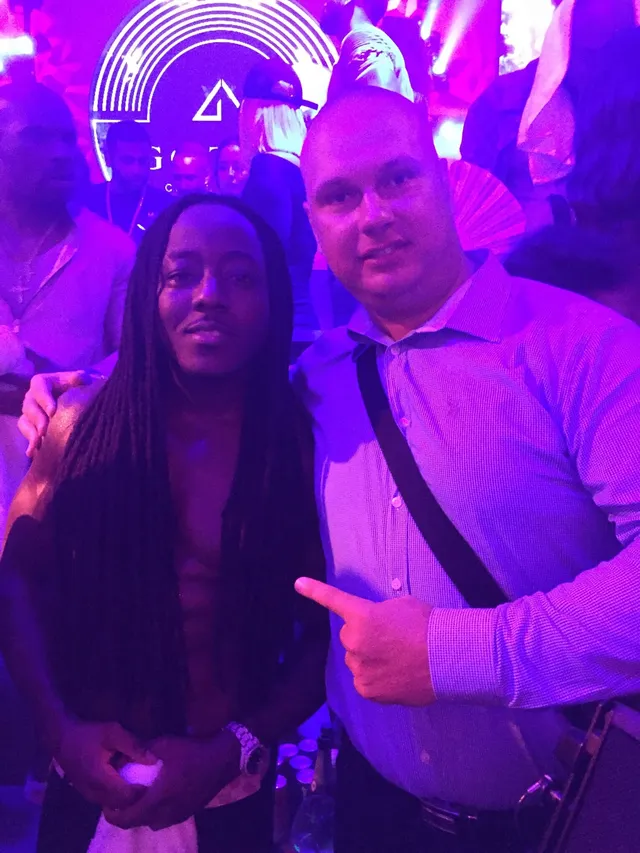 Two people posing in a nightclub under purple lighting