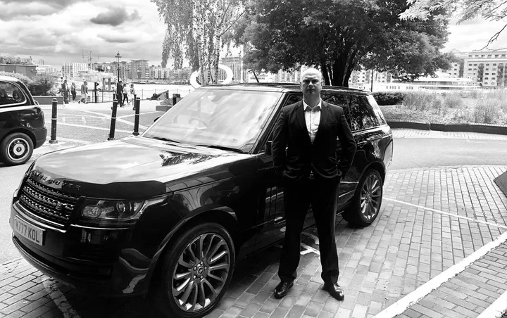 Private security officer standing beside a black SUV