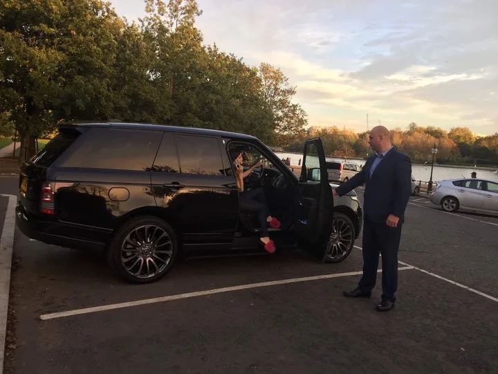 Secure chauffeur standing beside a black SUV