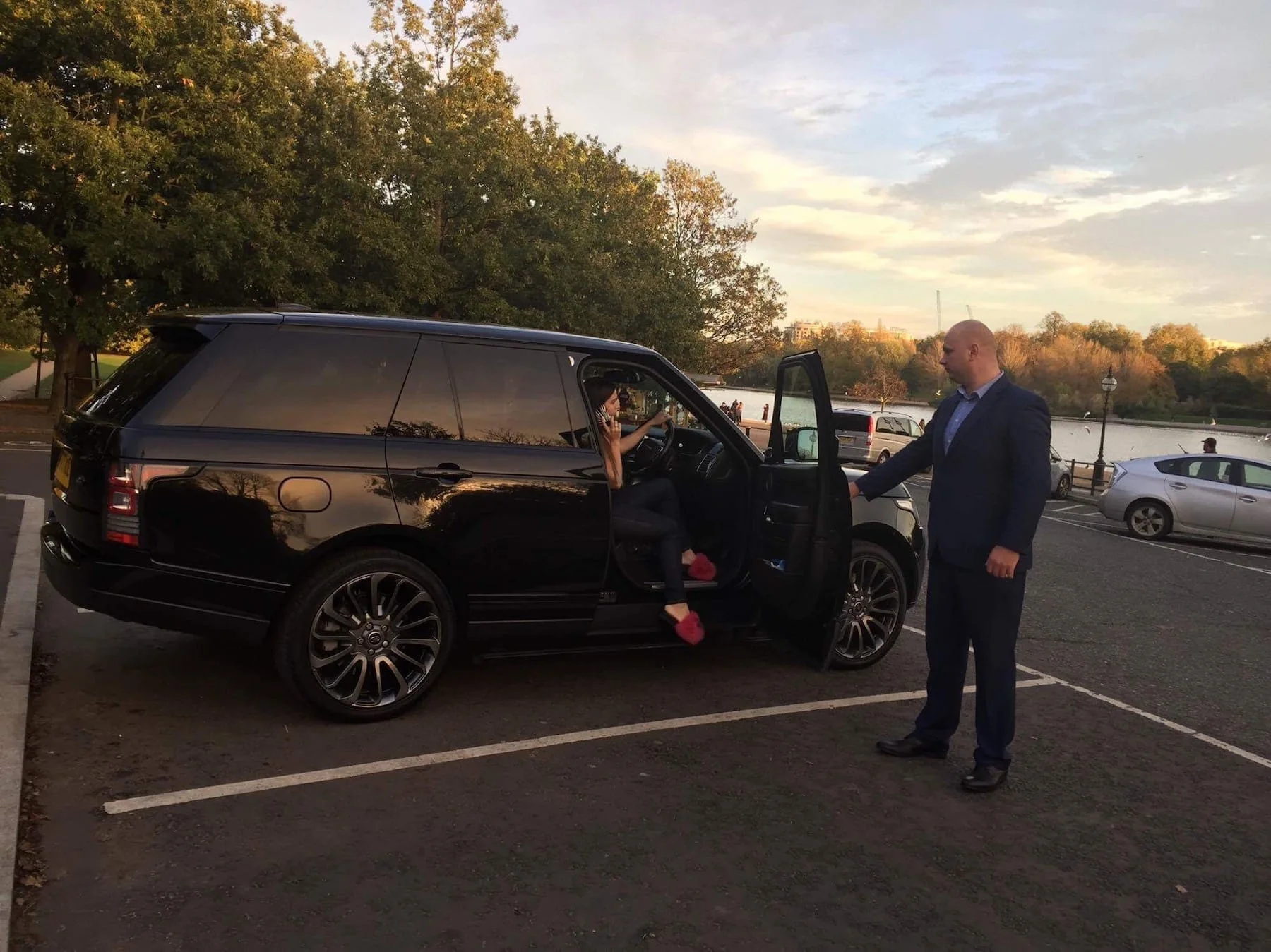 Secure chauffeur standing beside a black SUV