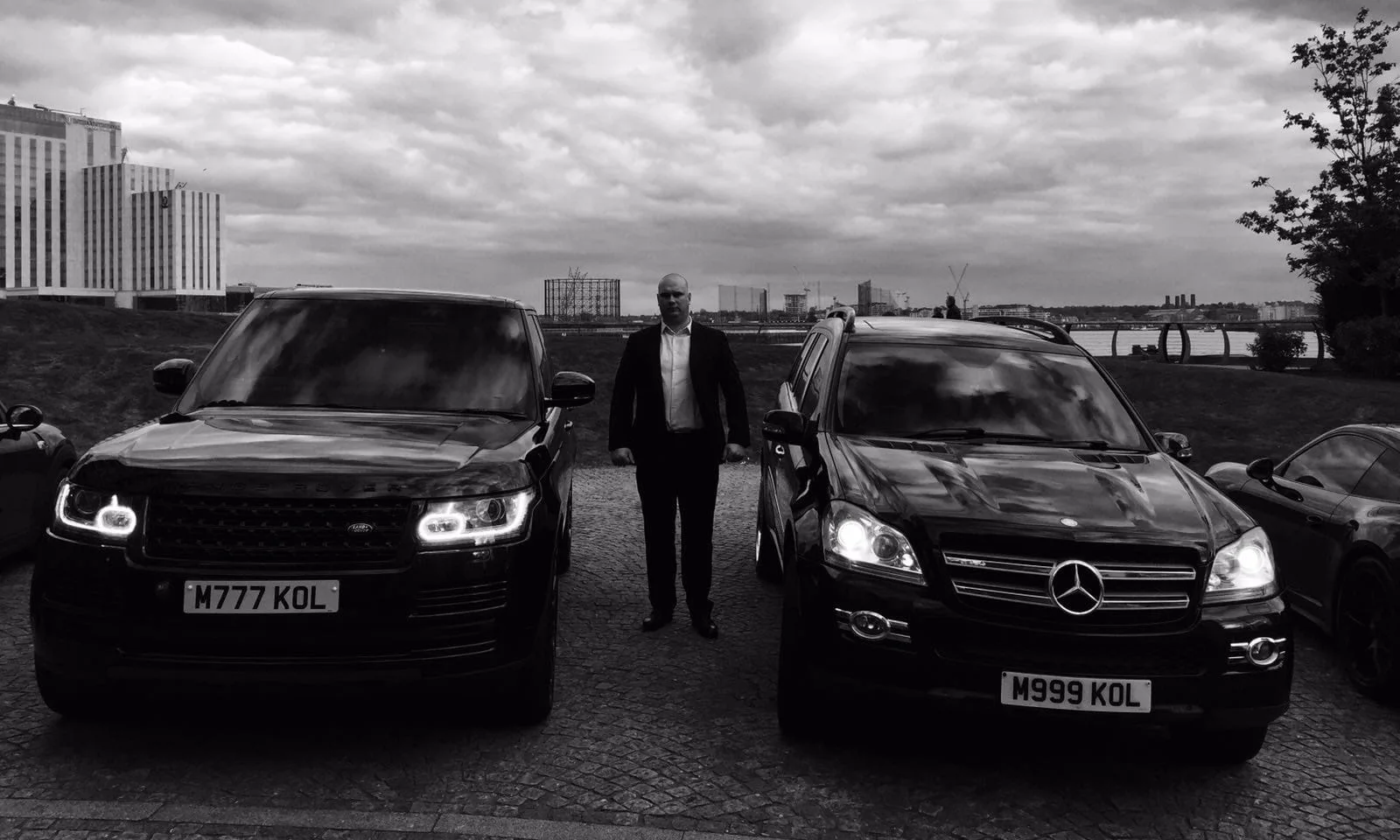 Security professional standing between two black SUVs